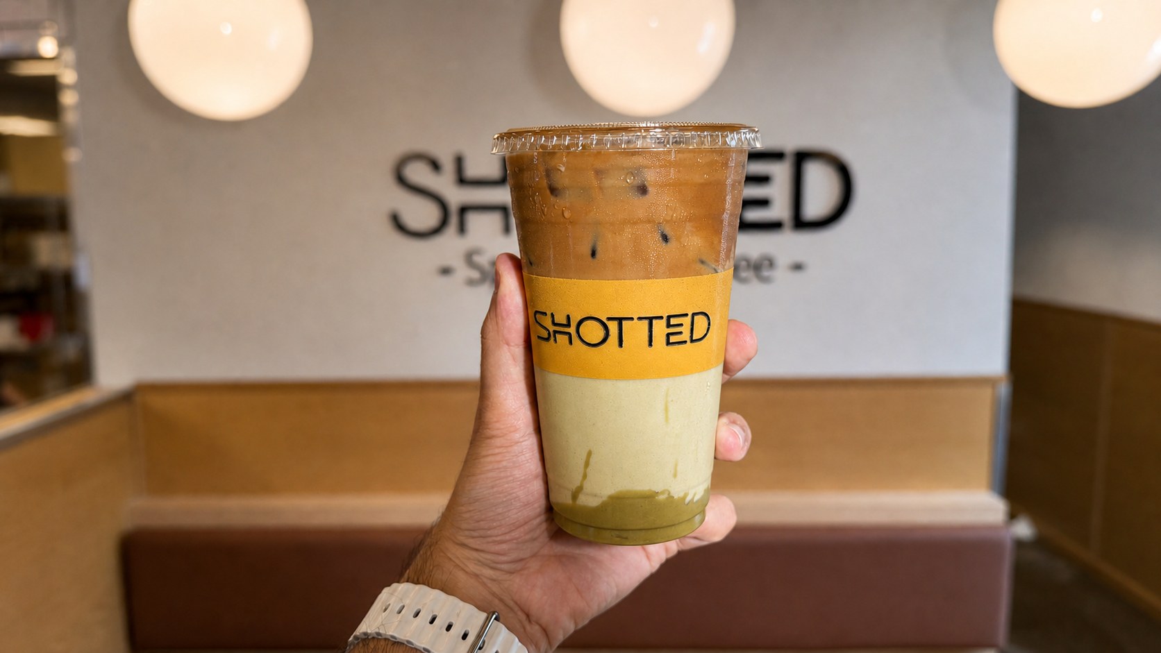 Layered iced Shotted Coffee specialty drink held inside the West Falls Church café