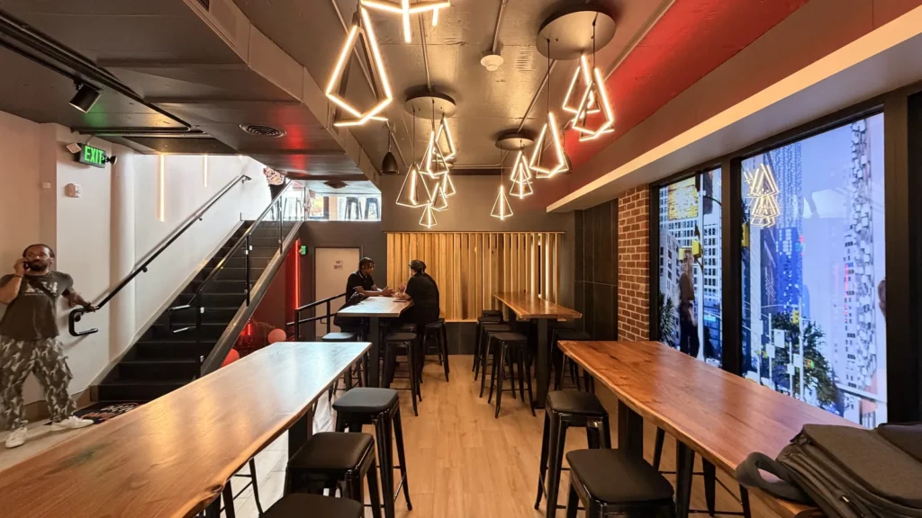 Flavor Hive’s Georgetown dining room with communal wood bar tables, black stools and geometric pendant lights