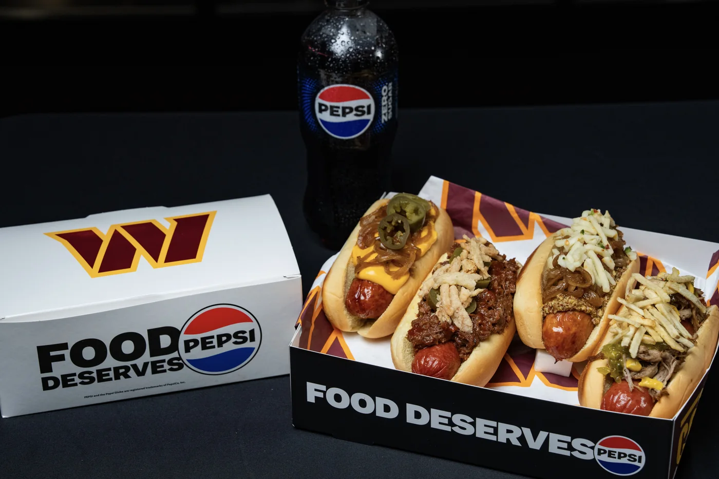 Four specialty Legends hot dogs with different toppings and a Pepsi bottle