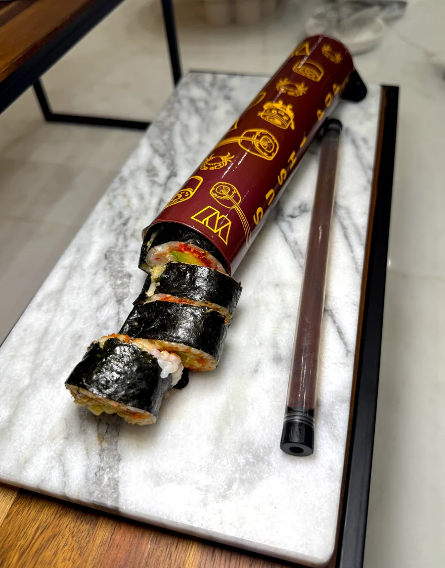 Sushi pieces emerging from a burgundy Commanders push-pop tube beside a sauce tube