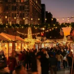 Crowds walking between lit vendor stalls under string lights and star decorations on F Street NW at the DowntownDC Holiday Market at dusk