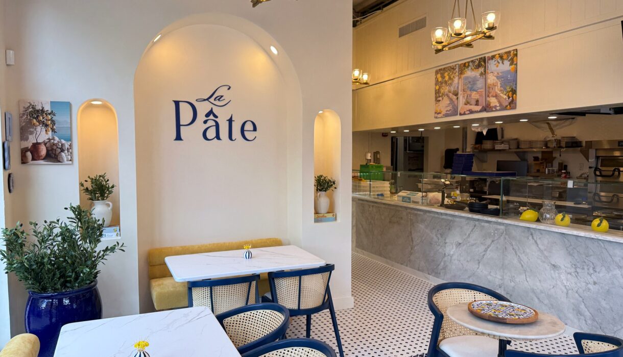 La Pâte dining room on U Street with blue chairs, marble tables and the restaurant name on the wall