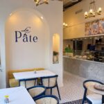 La Pâte dining room on U Street with blue chairs, marble tables and the restaurant name on the wall