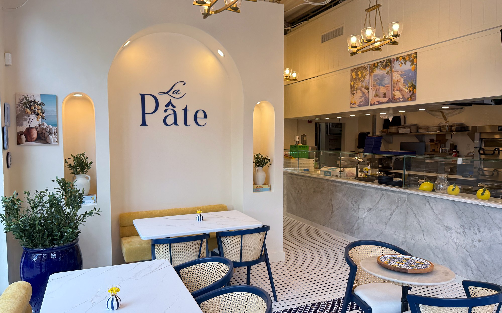 La Pâte dining room on U Street with blue chairs, marble tables and the restaurant name on the wall