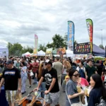 Crowds walking between food tents and boba and mango banners in the Fair Oaks Mall parking lot in Fairfax during an Asian night market this season