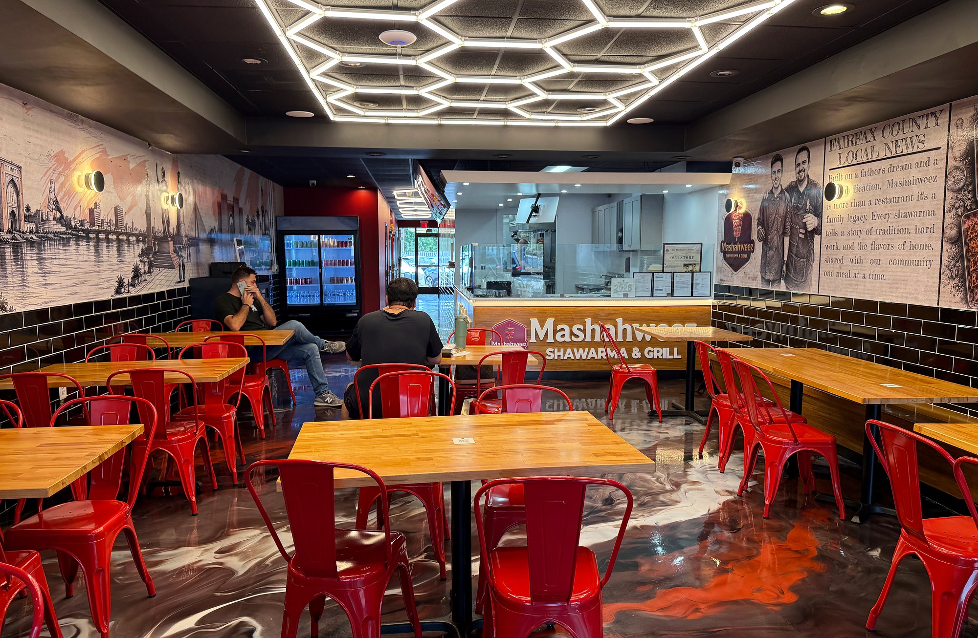 Mashahweez dining room with red chairs, geometric ceiling lights and a father-and-son mural