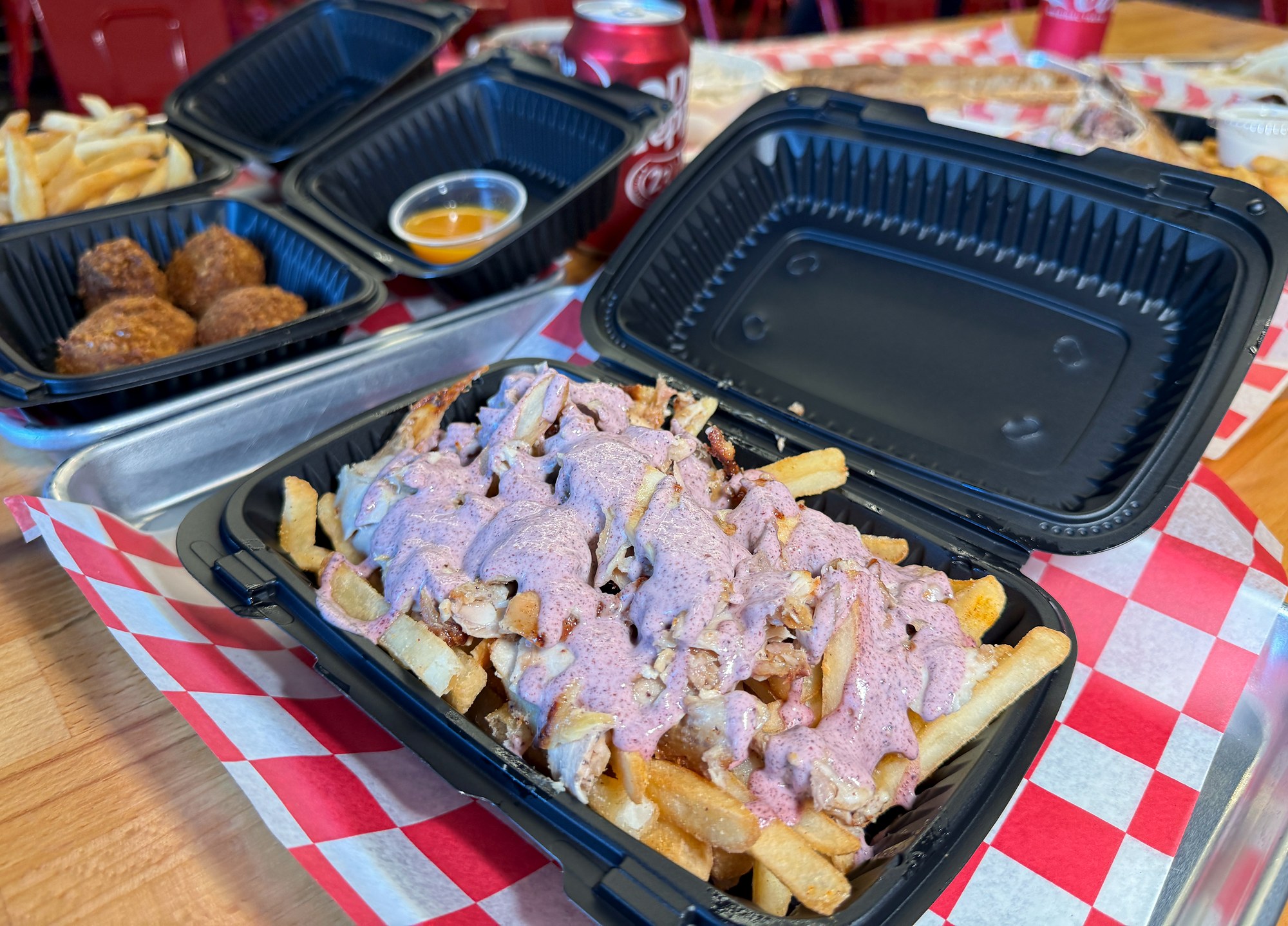 Shawarma-loaded fries topped with pink sauce at Mashahweez in Vienna