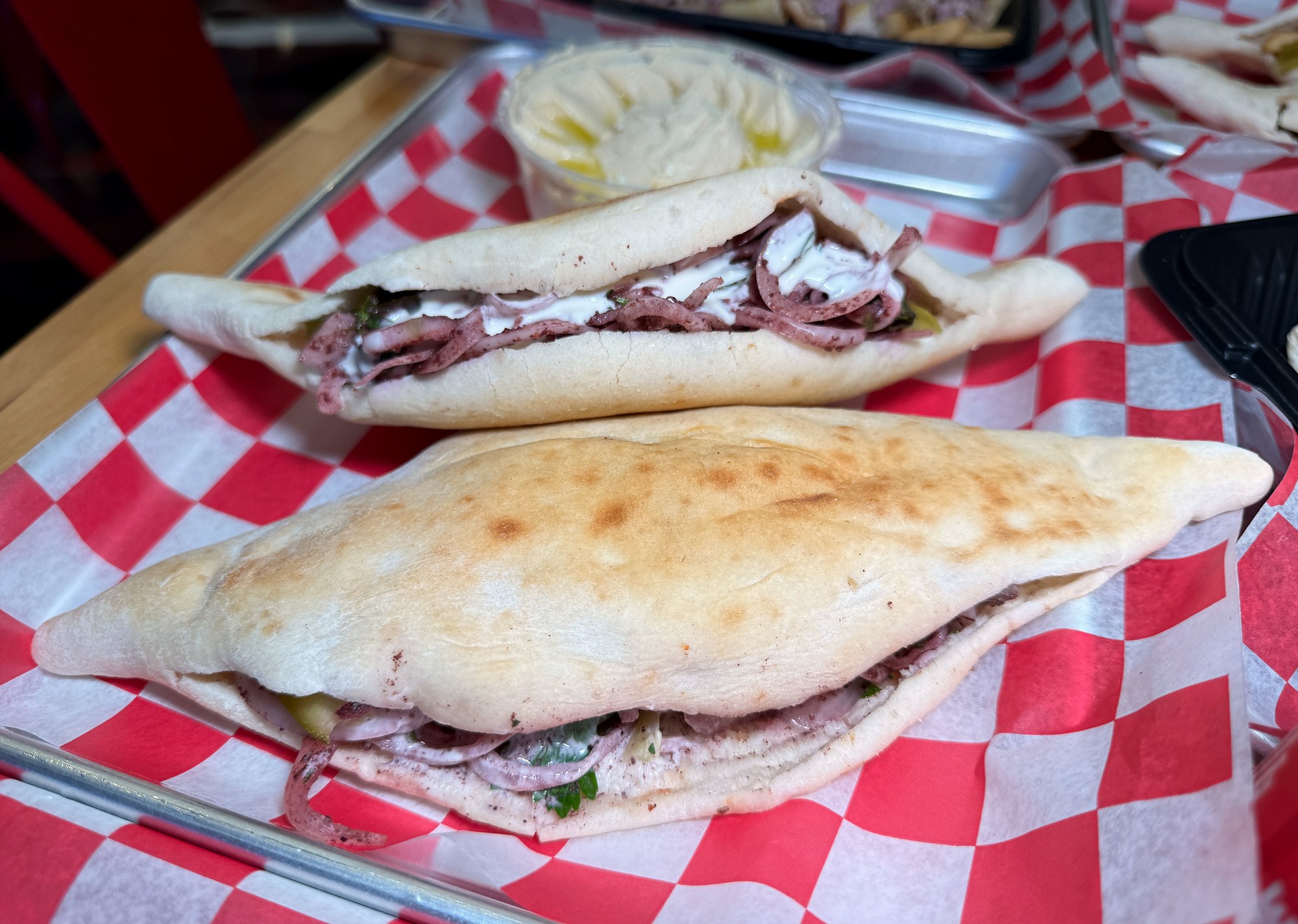 Two shawarma sandwiches in Iraqi samoon bread with hummus at Mashahweez