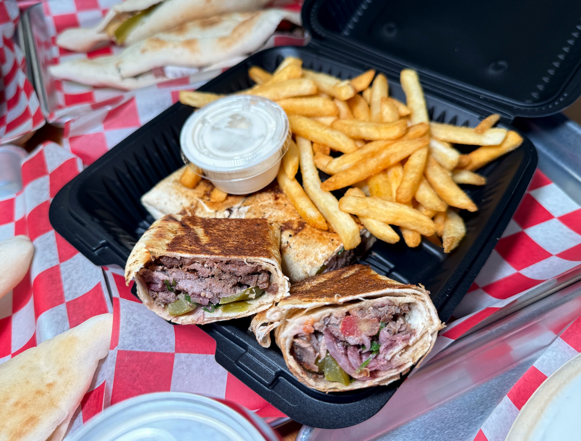 Cut shawarma wrap with fries and sauce at Mashahweez Shawarma & Grill in Vienna