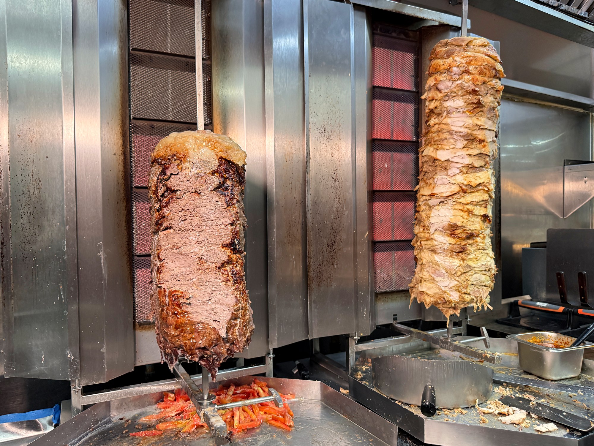 Chicken and beef shawarma cooking on vertical spits at Mashahweez in Vienna