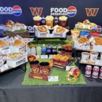 Commanders 2026 food spread at Northwest Stadium with burgers, hot dogs, pretzels, chili and member price signs