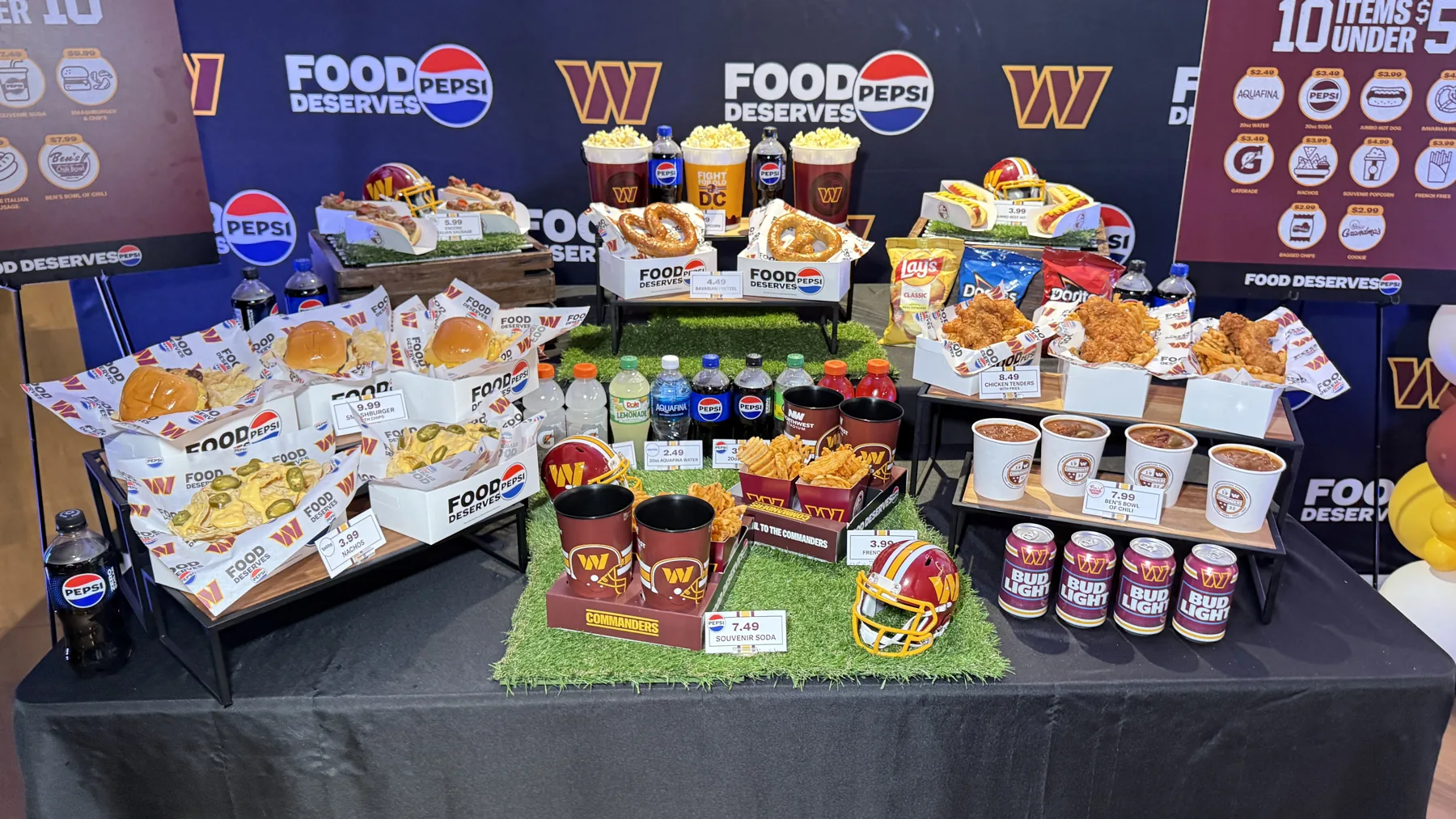 Commanders 2026 food spread at Northwest Stadium with burgers, hot dogs, pretzels, chili and member price signs