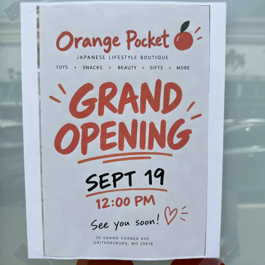 Orange Pocket grand opening flyer taped to the store window: September 19, 12:00 p.m., 30 Grand Corner Ave, Gaithersburg