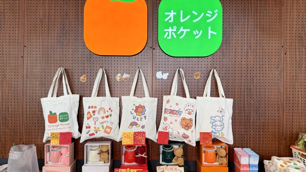 Orange Pocket tote bags and magnets displayed on a wooden wall inside the Gaithersburg store