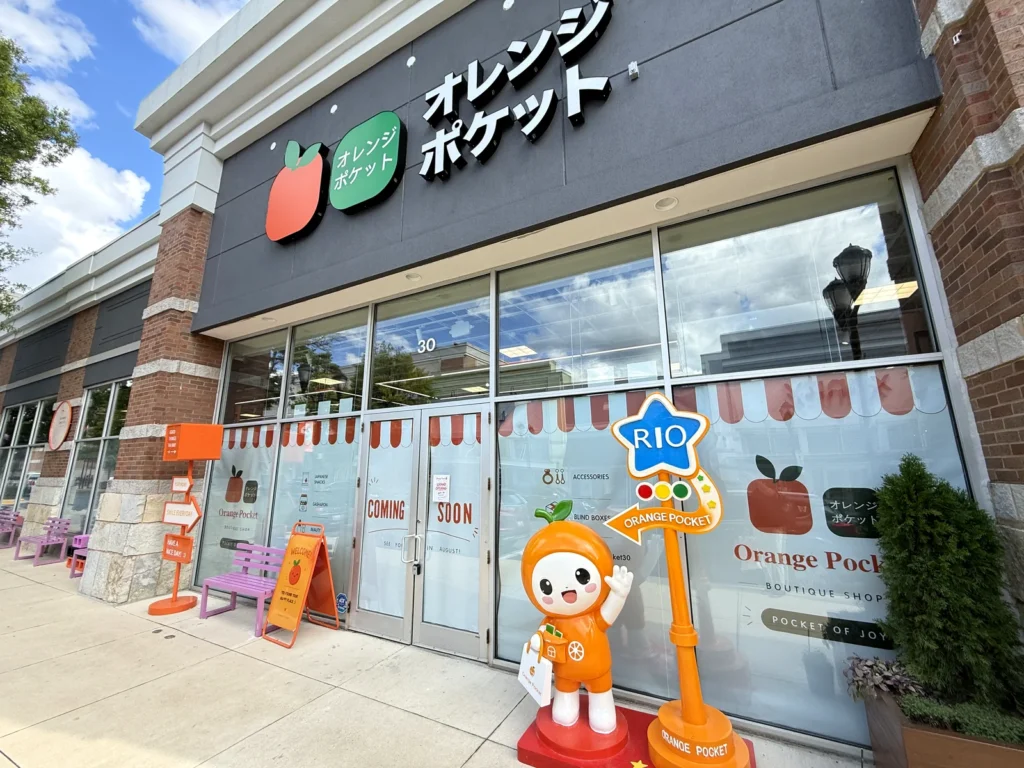 Orange Pocket storefront at Rio Lakefront in Gaithersburg before opening, with its orange mascot statue and a Rio sign outside the doors