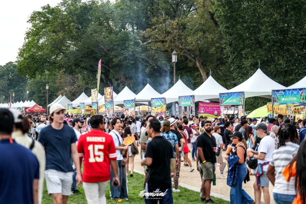 Crowds walking past rows of white Thai food vendor tents at the 2025 Sawasdee DC Thai Festival on the National Mall in Washington DC