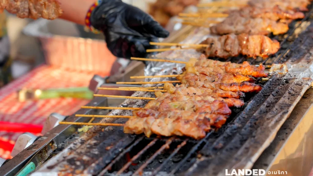 Skewers of grilled pork and chicken satay on a charcoal grill at a Sawasdee DC food stall