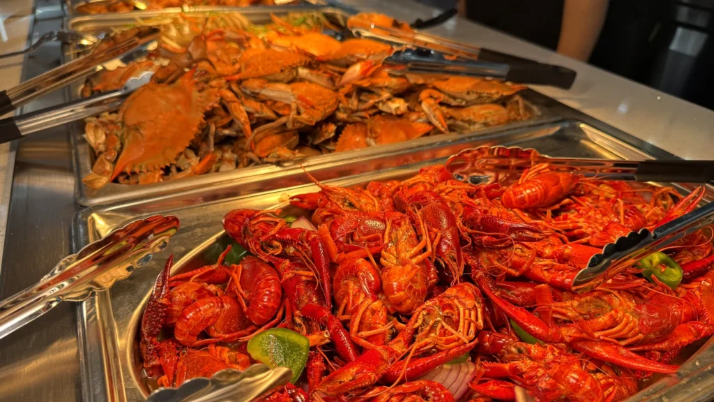 Steamed blue crabs and spicy crawfish in trays at the UMI Alexandria seafood line