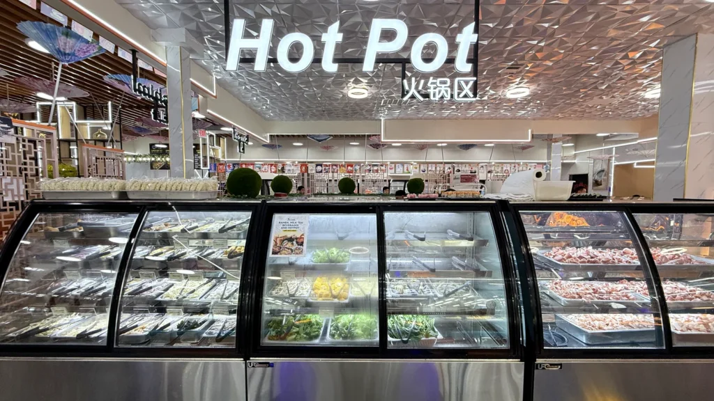 The Hot Pot section at UMI Alexandria: a refrigerated case of hot pot ingredients under the Hot Pot sign, with the sauce bar behind