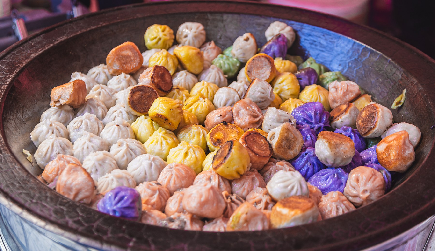 Colorful dumplings cooking in a large pan at a previous Asia in a Bite event