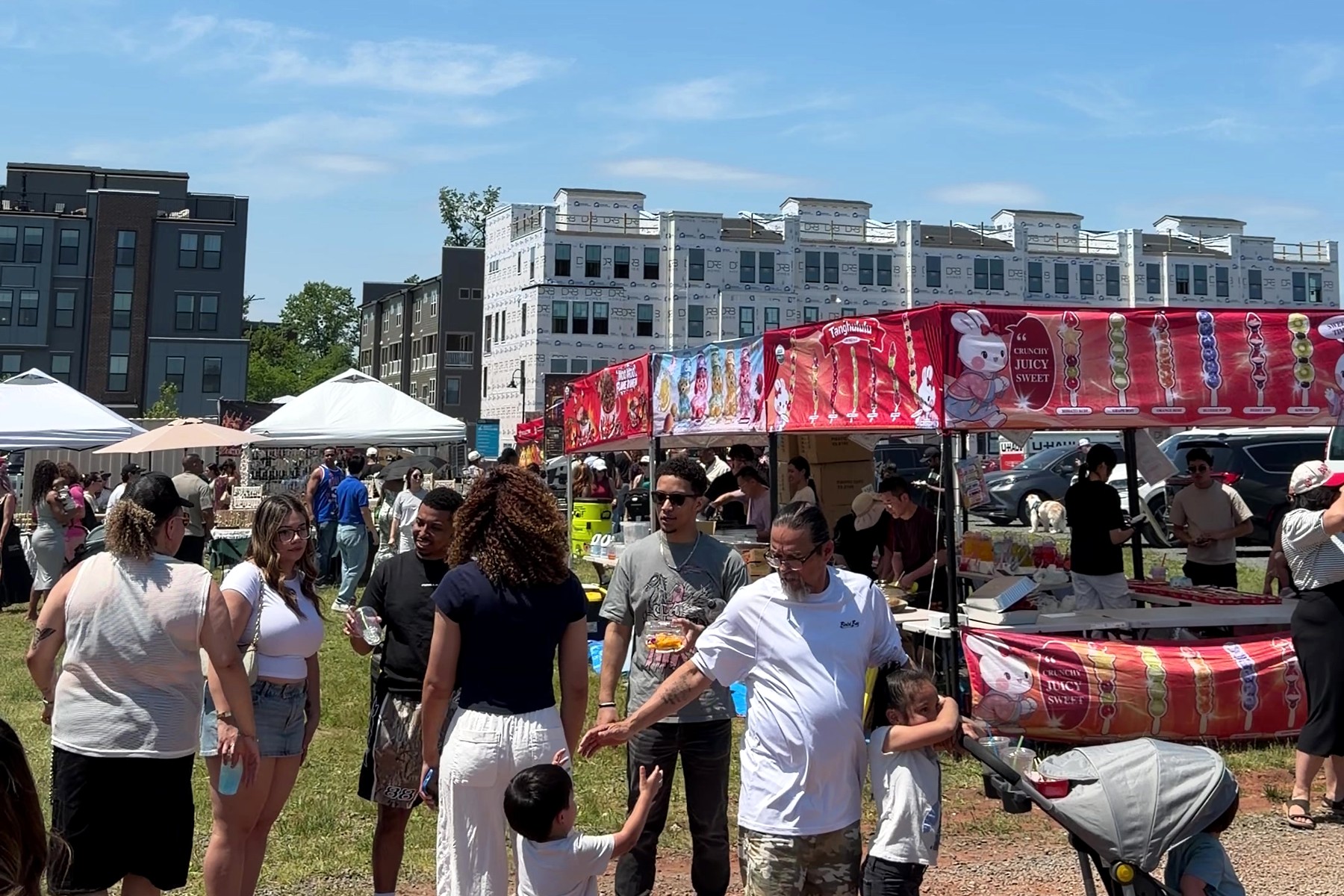 Crowds browsing rows of Asian food stalls on a sunny day at a previous Asia in a Bite festival