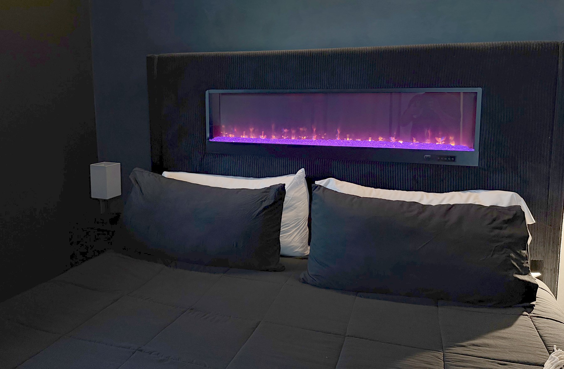 King bed and illuminated fireplace in a bedroom at Luray Yurt