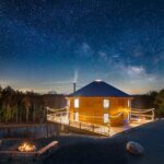 Luray Yurt at night with a star-filled sky, glowing deck lights, and a fire pit