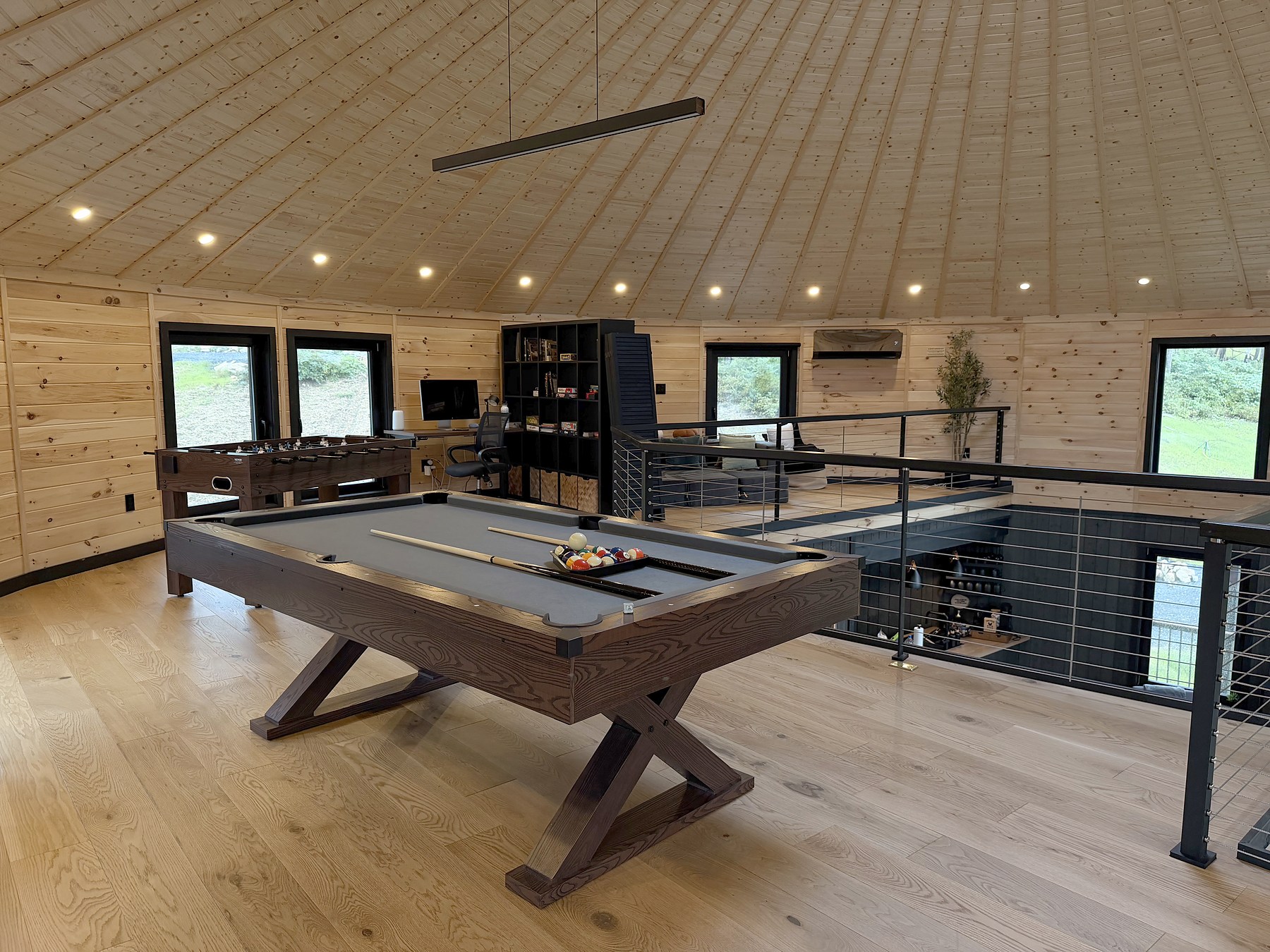 Pool table and seating beneath the wood ceiling in Luray Yurt’s loft