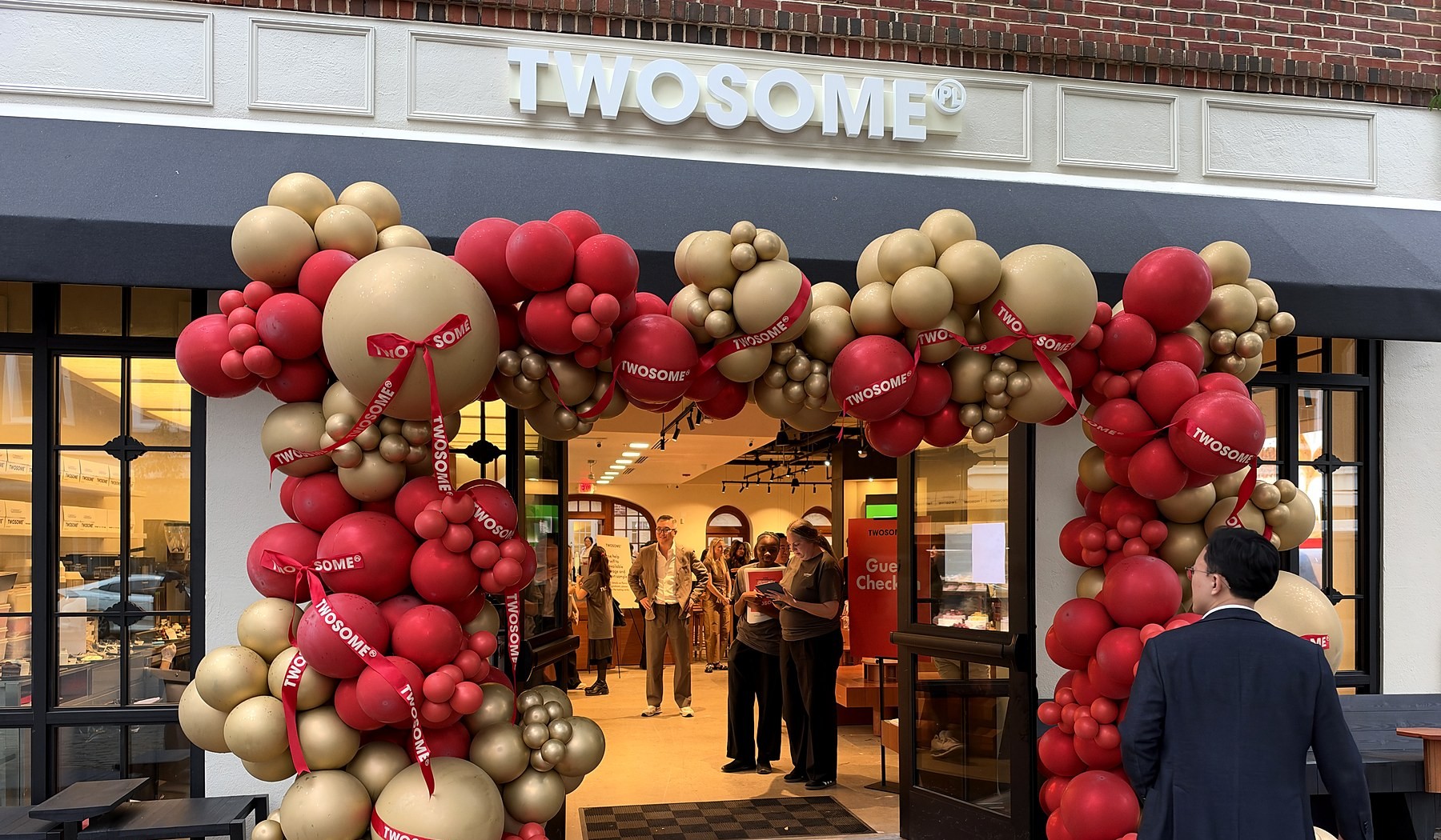Twosome Place sign above the red and gold balloon arch at its Old Town Alexandria entrance