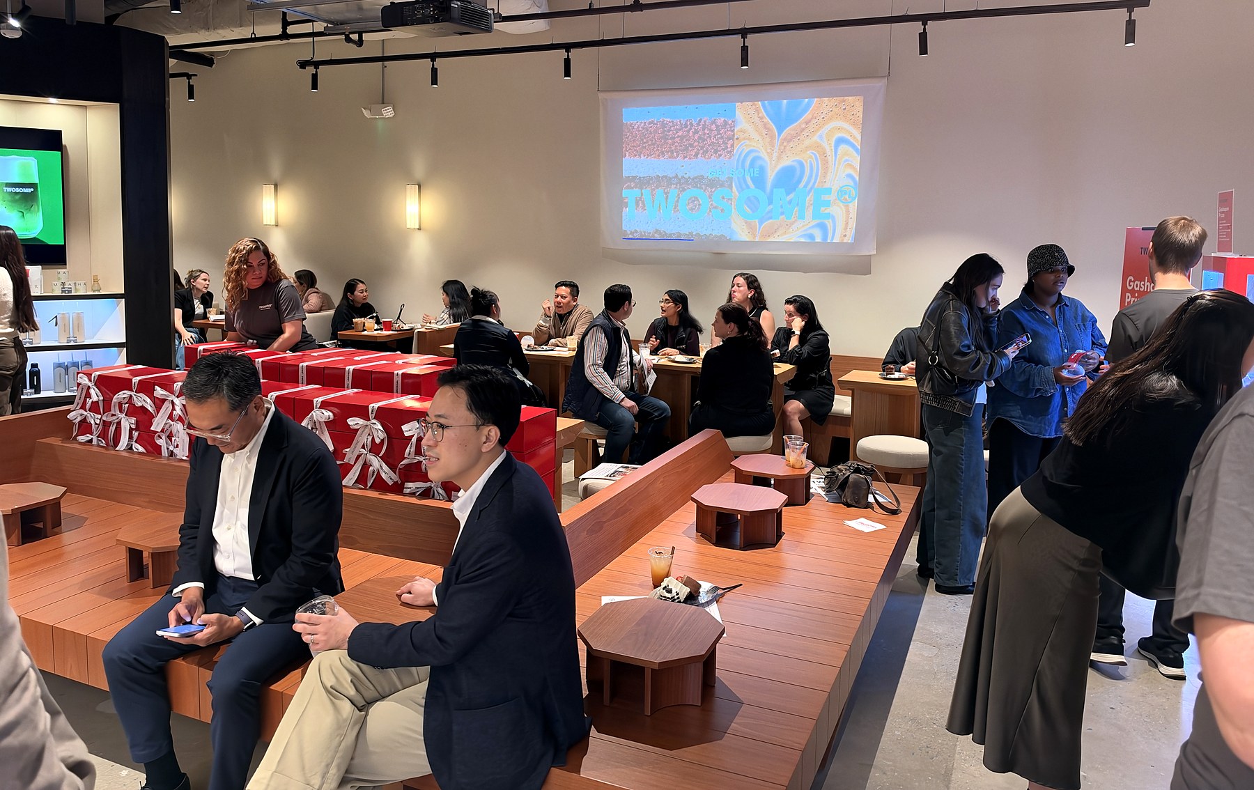 Guests seated around wooden tables inside Twosome Place during its Old Town Alexandria preview