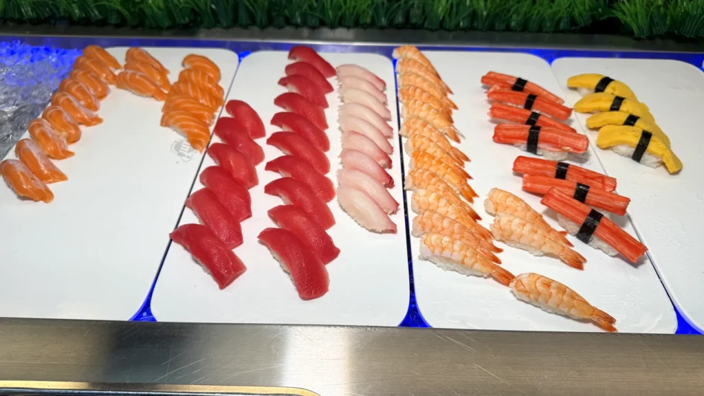 Trays of salmon, tuna and shrimp nigiri and sashimi on the sushi station at Yami Buffet in Alexandria
